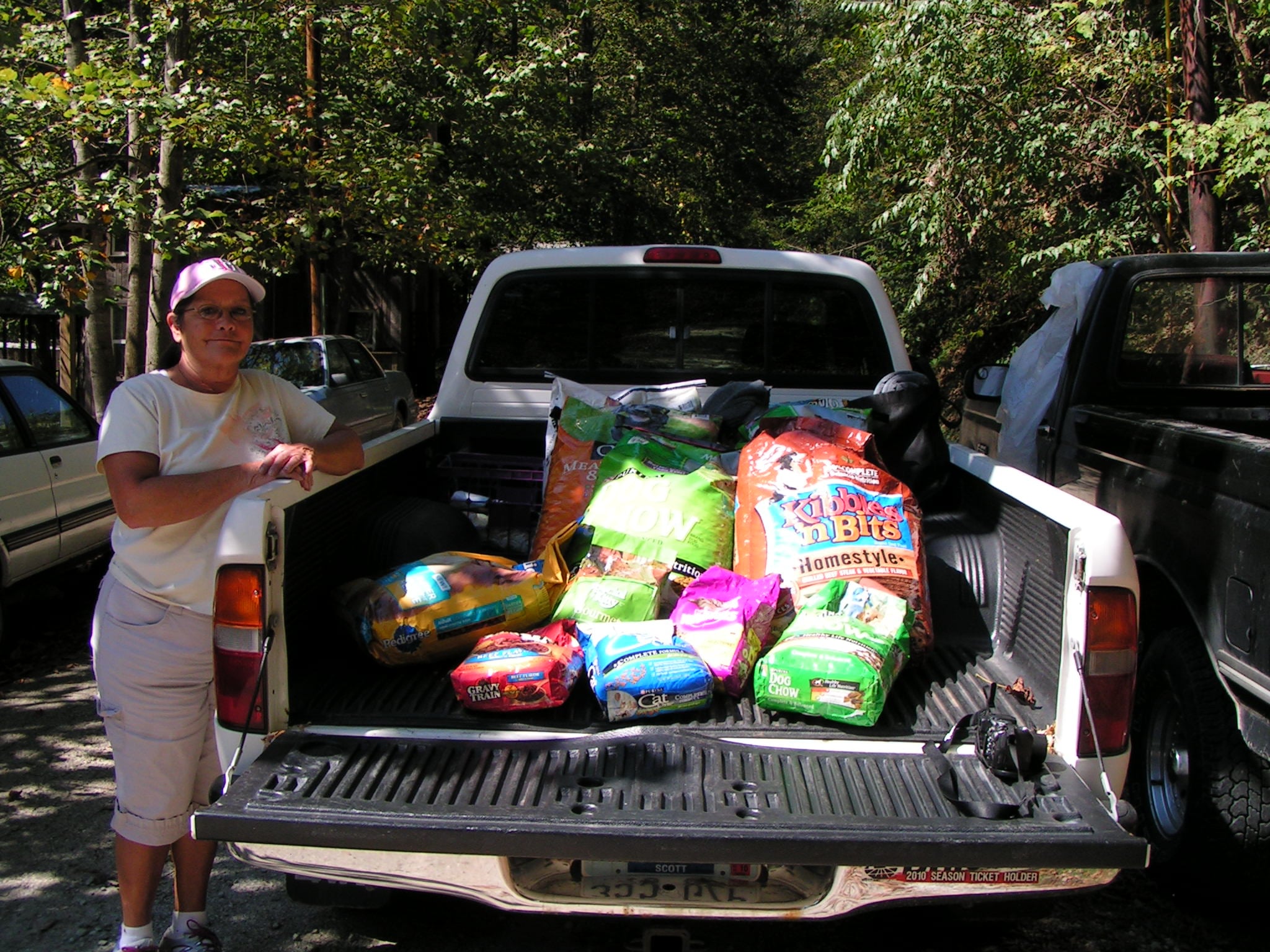 A volunteer beside a pickup truck loaded with animal food