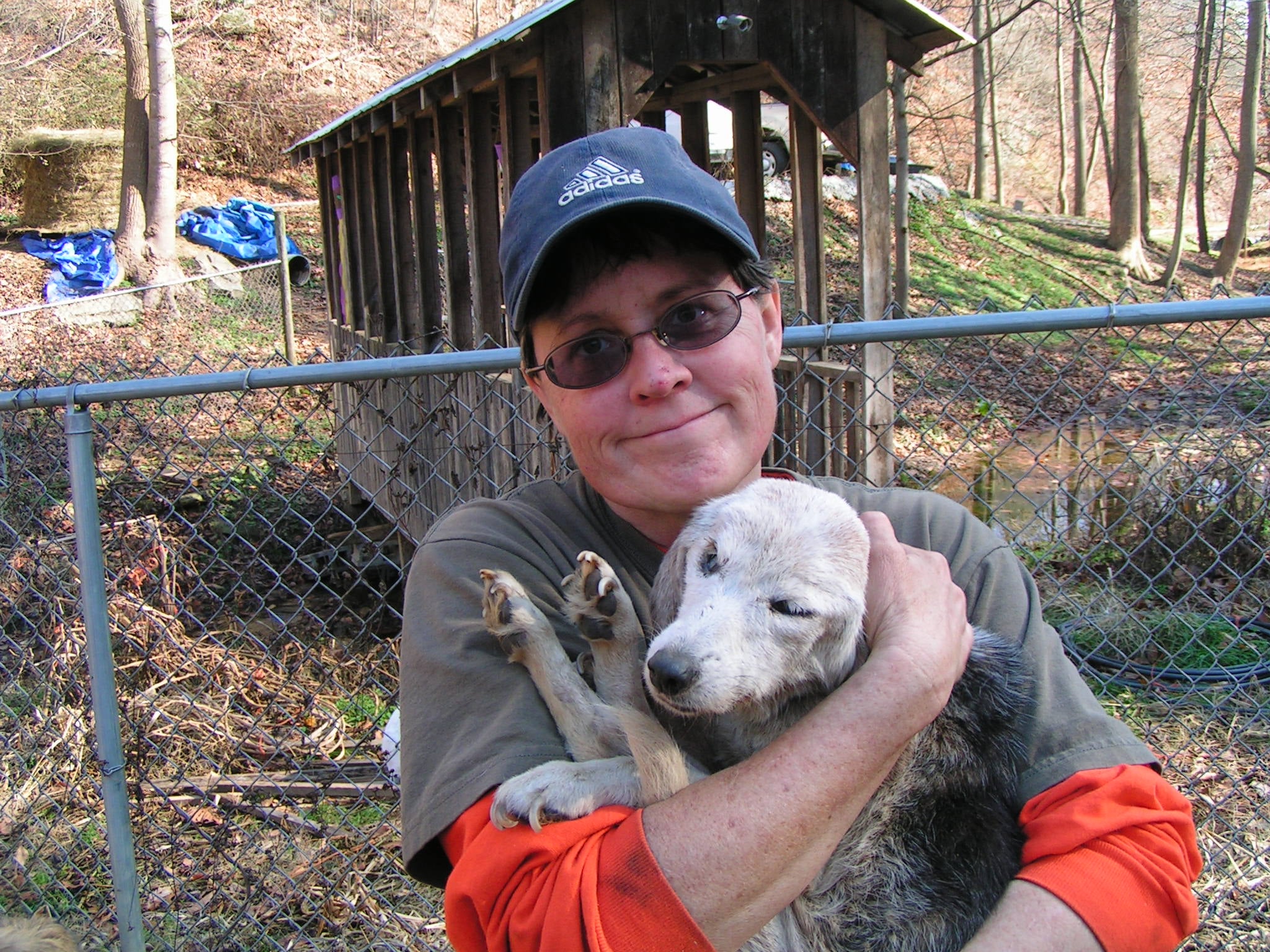 A person holding a puppy beside a kennel