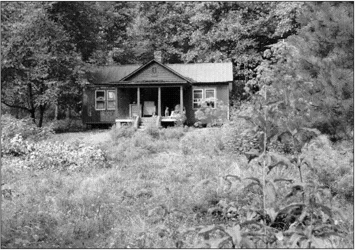 Black-and-white view of a simple hillside building and porch.