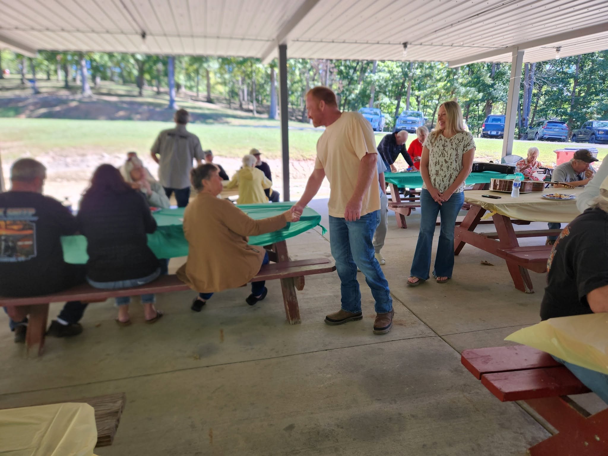 People gathered around tables beneath an open-sided pavilion.
